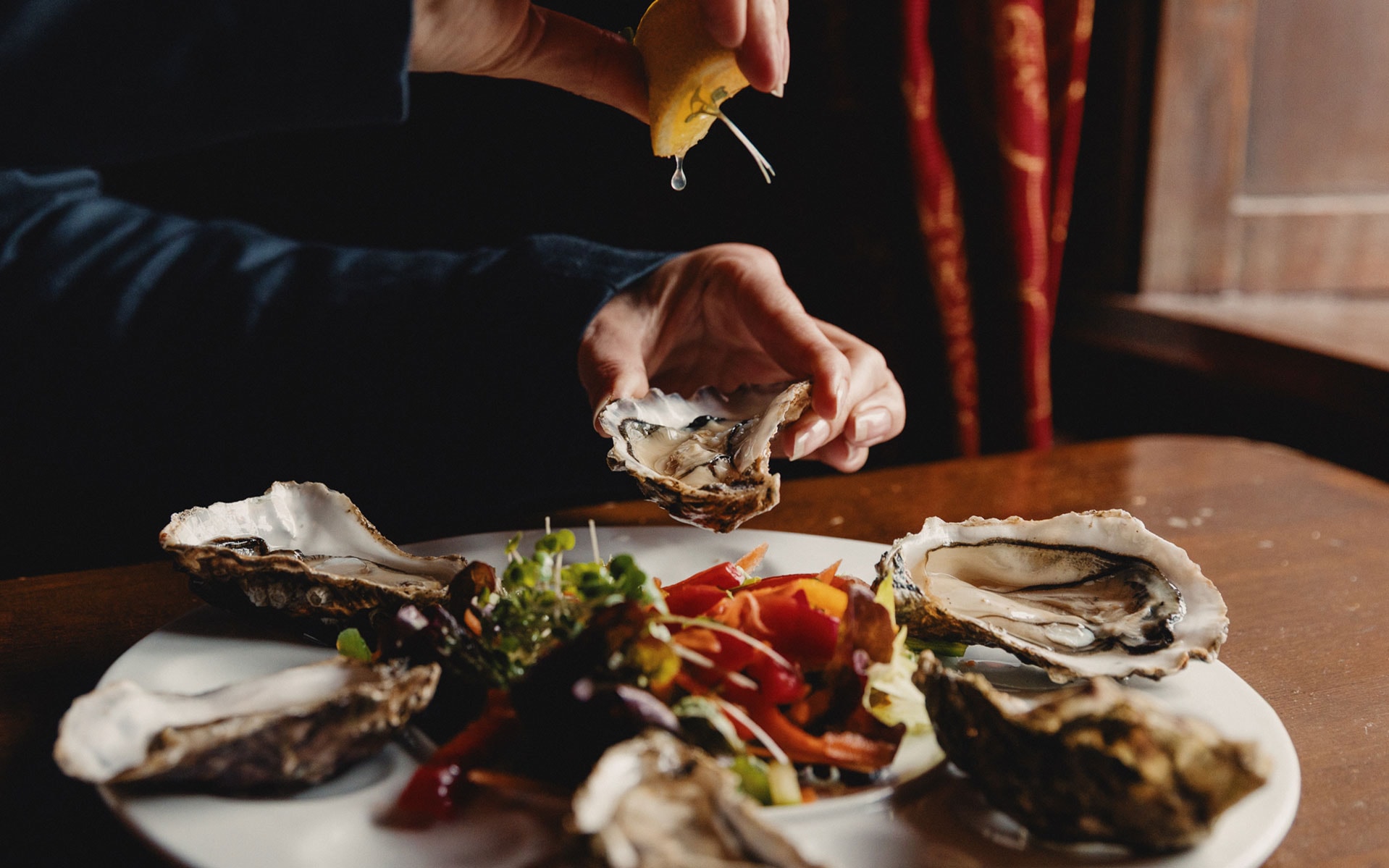 A person putting lemon juice on an oyster