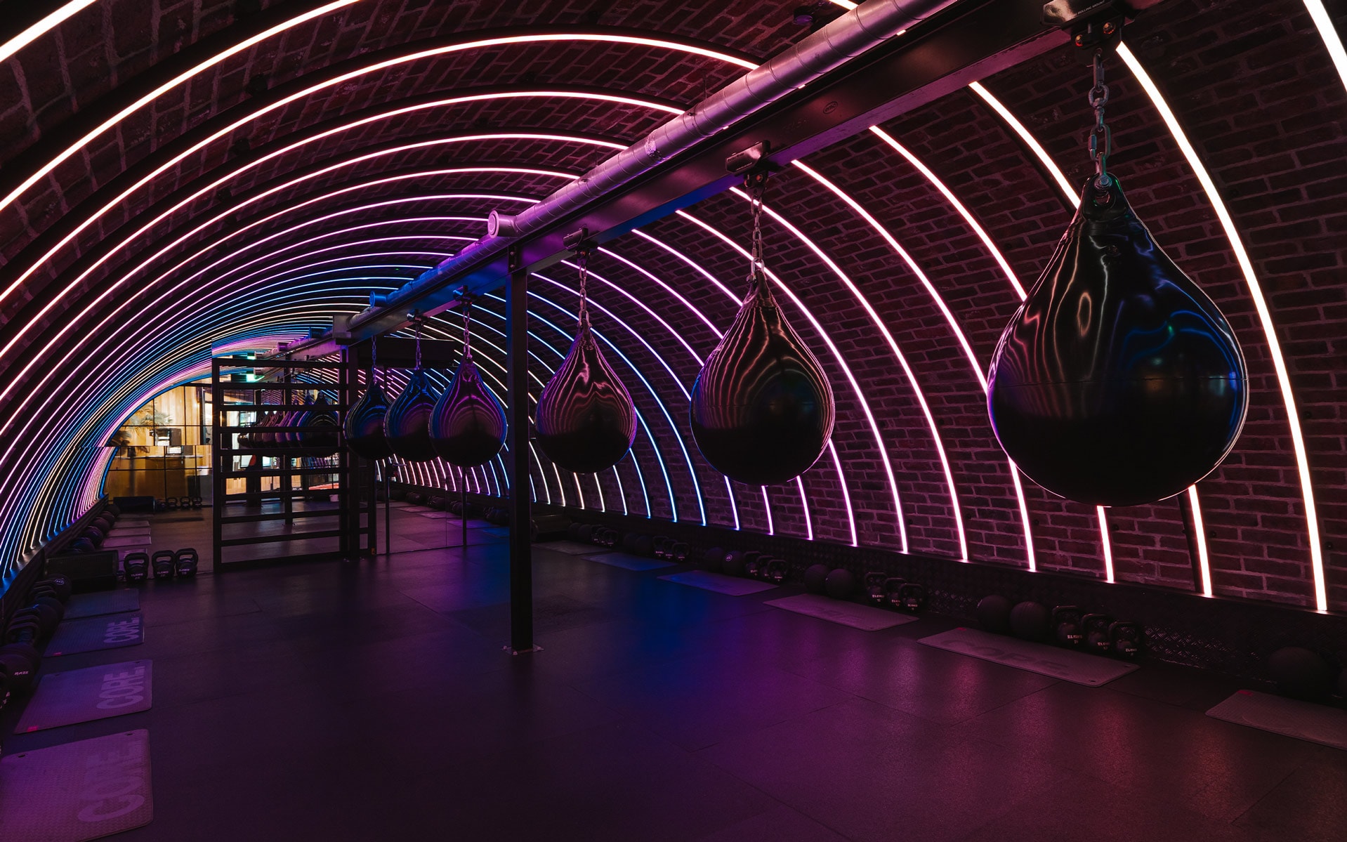 Black punching bags in a neon tunnel